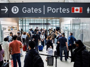 Travellers crowd the security queue in the departures lounge at the start of the Victoria Day holiday long weekend at Toronto Pearson International Airport in Mississauga on May 20, 2022.